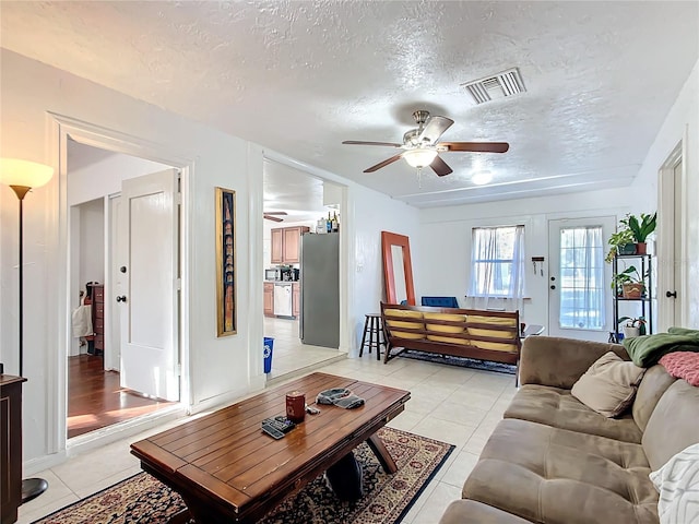 living area with light tile patterned floors, ceiling fan, a textured ceiling, and visible vents