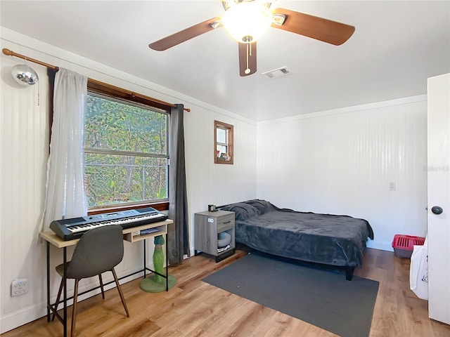 bedroom featuring a baseboard heating unit, visible vents, ceiling fan, and wood finished floors