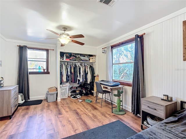 bedroom featuring wood finished floors, visible vents, baseboards, a ceiling fan, and a closet