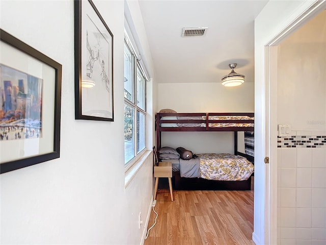 bedroom featuring visible vents, tile walls, and wood finished floors