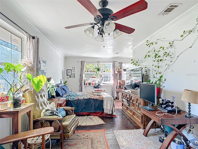 bedroom with ceiling fan, visible vents, wood finished floors, and ornamental molding