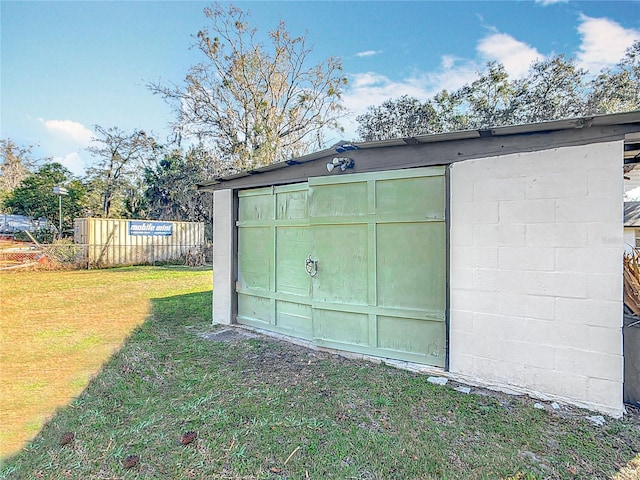 view of outdoor structure featuring driveway, fence, and an outbuilding