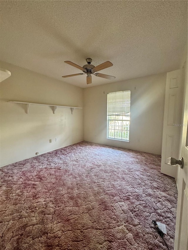 carpeted spare room featuring a textured ceiling and ceiling fan