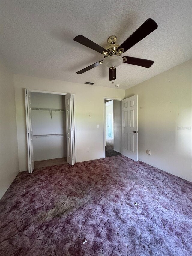 unfurnished bedroom with carpet flooring, a textured ceiling, ceiling fan, and a closet