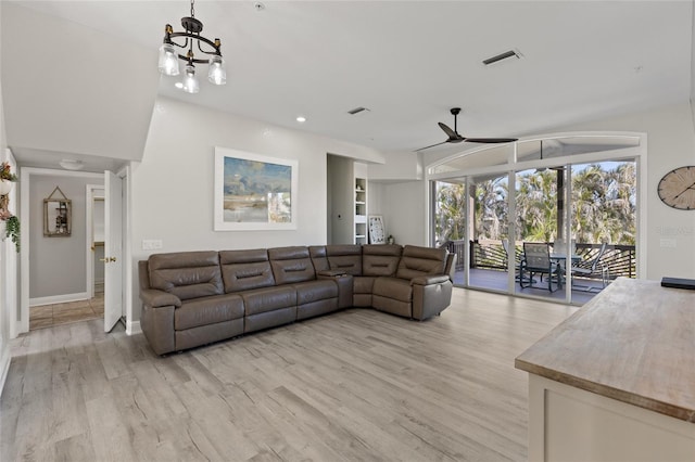 living room with ceiling fan with notable chandelier and light hardwood / wood-style floors