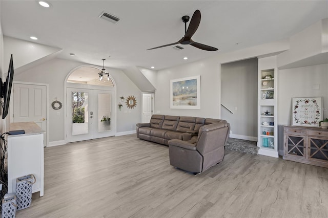 living room featuring lofted ceiling, built in shelves, light hardwood / wood-style flooring, and french doors