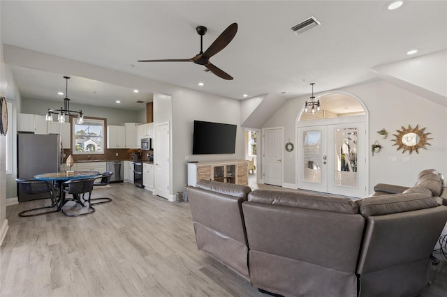 living room with french doors, ceiling fan with notable chandelier, and light wood-type flooring