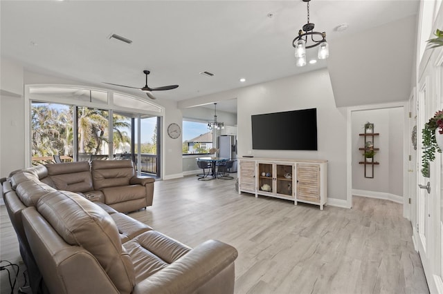 living room with ceiling fan with notable chandelier and light hardwood / wood-style flooring