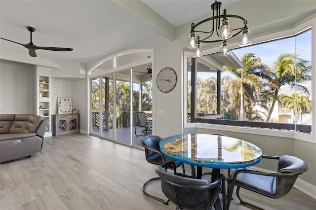 dining space featuring beam ceiling, hardwood / wood-style floors, ceiling fan with notable chandelier, and built in shelves