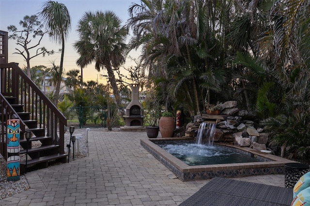 patio terrace at dusk featuring exterior fireplace