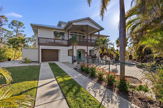 view of front of house with a garage, a balcony, a front yard, and ceiling fan