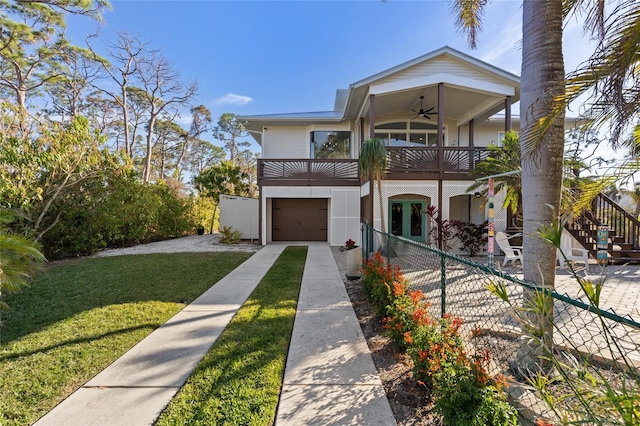 view of front facade with ceiling fan, a garage, a balcony, and a front lawn