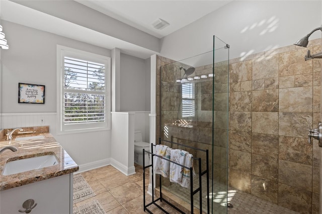 bathroom with vanity, tile patterned flooring, toilet, and tiled shower