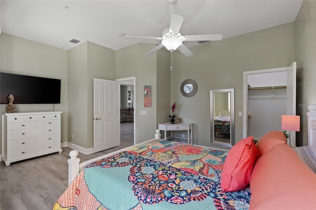 bedroom featuring a high ceiling, a spacious closet, ceiling fan, and light wood-type flooring