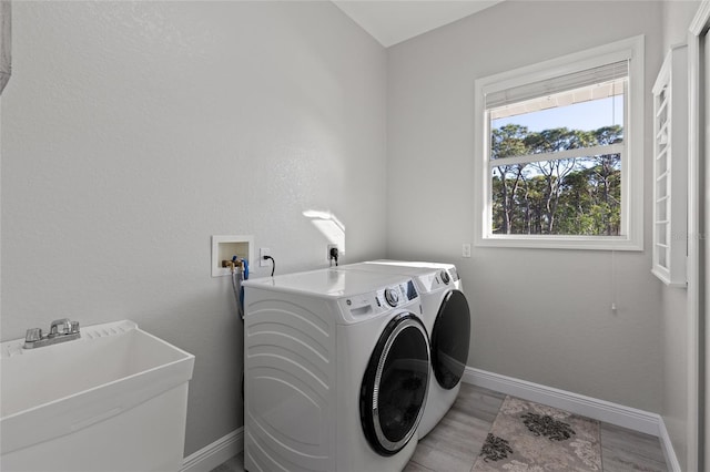 laundry area with washing machine and clothes dryer, light hardwood / wood-style floors, and sink