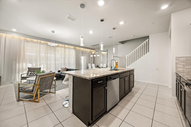 kitchen with a kitchen island with sink, sink, pendant lighting, and stainless steel dishwasher