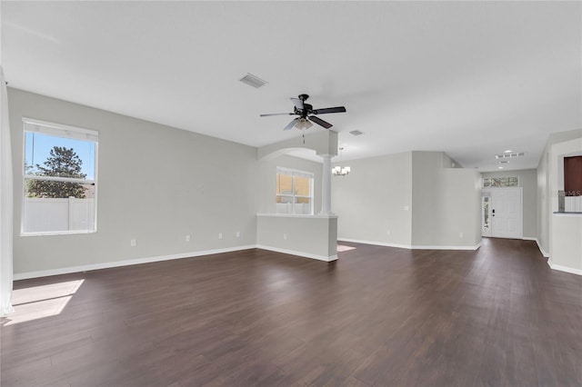 unfurnished living room featuring ceiling fan with notable chandelier and dark hardwood / wood-style flooring