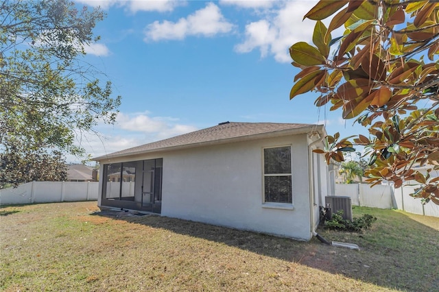 rear view of house featuring a sunroom, central AC, and a lawn