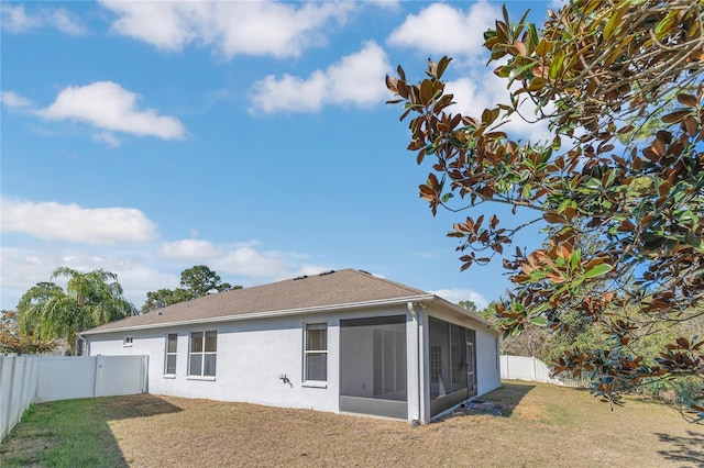 rear view of house featuring a lawn and a sunroom