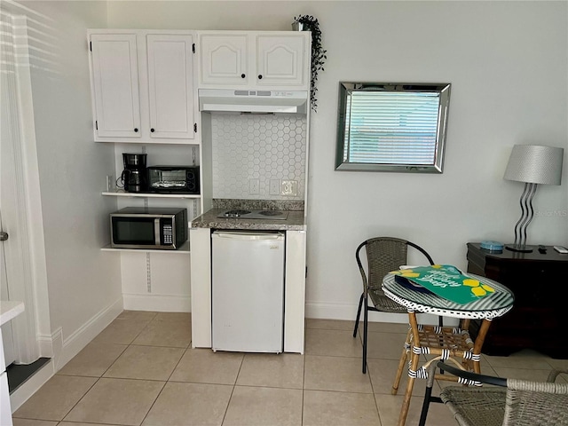 kitchen featuring tasteful backsplash, light tile patterned flooring, fridge, and white cabinets