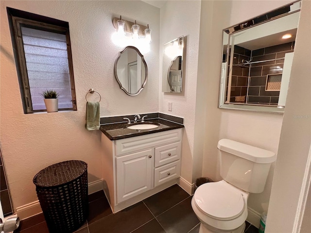 bathroom with vanity, tile patterned floors, toilet, and a tile shower