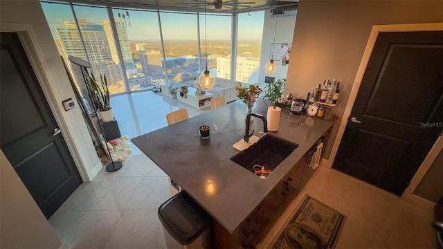 interior space with ceiling fan, a wall of windows, sink, and a wealth of natural light