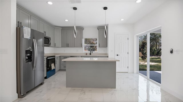 kitchen featuring sink, gray cabinetry, decorative light fixtures, appliances with stainless steel finishes, and a kitchen island