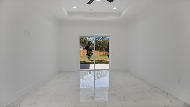 spare room featuring ceiling fan and a raised ceiling