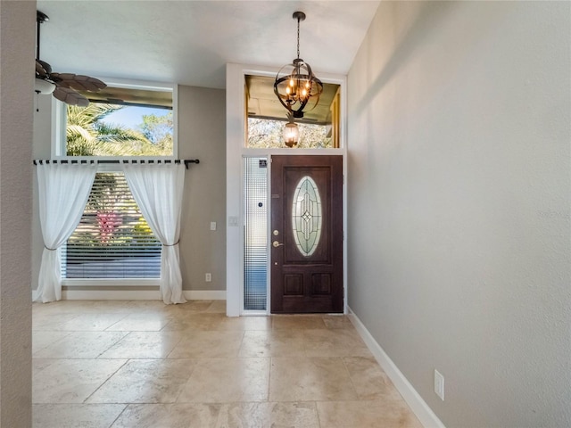 foyer with ceiling fan with notable chandelier and a wealth of natural light