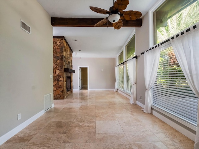 unfurnished living room featuring beamed ceiling, ceiling fan, and a stone fireplace