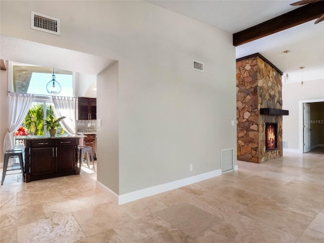 unfurnished living room featuring a stone fireplace and beam ceiling