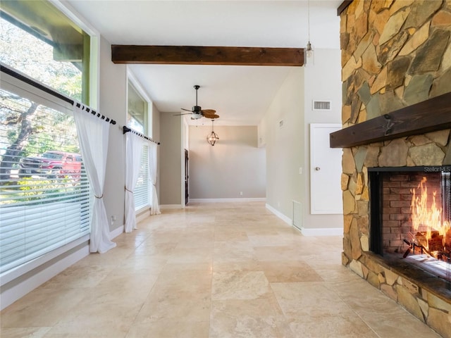 entrance foyer featuring ceiling fan, a wealth of natural light, a fireplace, and beamed ceiling