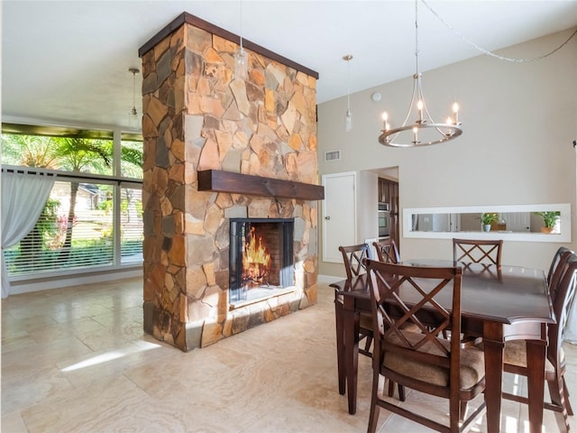 dining room with an inviting chandelier and a stone fireplace