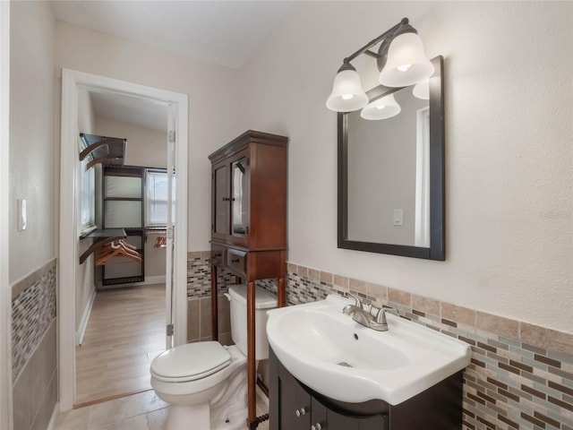 bathroom featuring tile patterned floors, vanity, toilet, and tile walls