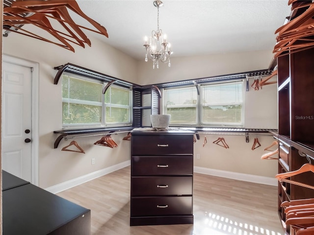 spacious closet featuring light hardwood / wood-style flooring and a notable chandelier