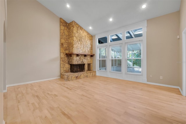 unfurnished living room with a fireplace, high vaulted ceiling, and light wood-type flooring