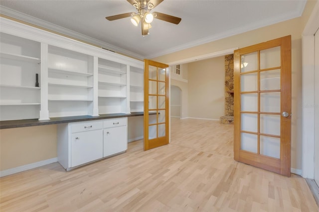 unfurnished office featuring built in desk, ornamental molding, french doors, and light wood-type flooring