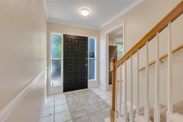 foyer entrance with light tile patterned floors, a wealth of natural light, ornamental molding, and a textured ceiling