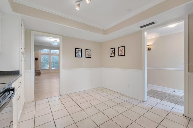 empty room featuring light tile patterned floors, crown molding, track lighting, and a raised ceiling