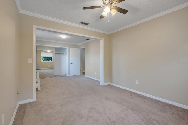 carpeted spare room featuring ceiling fan, crown molding, and a textured ceiling