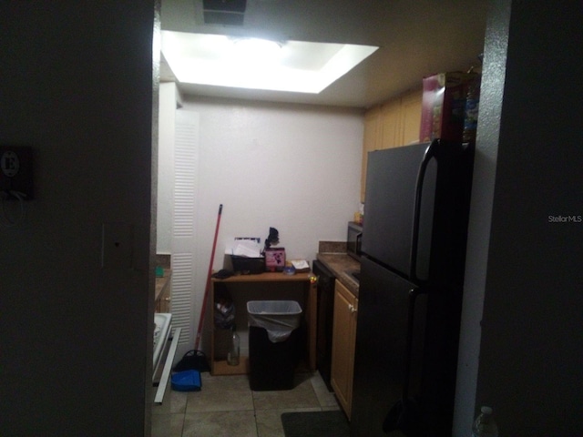 kitchen featuring light tile patterned flooring and black refrigerator