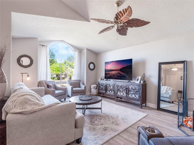 living room featuring vaulted ceiling, ceiling fan, a textured ceiling, and light wood-type flooring