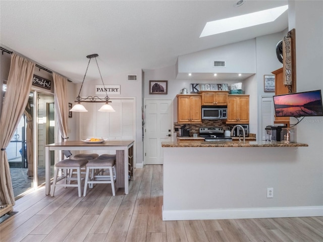 kitchen with pendant lighting, kitchen peninsula, stone counters, and appliances with stainless steel finishes