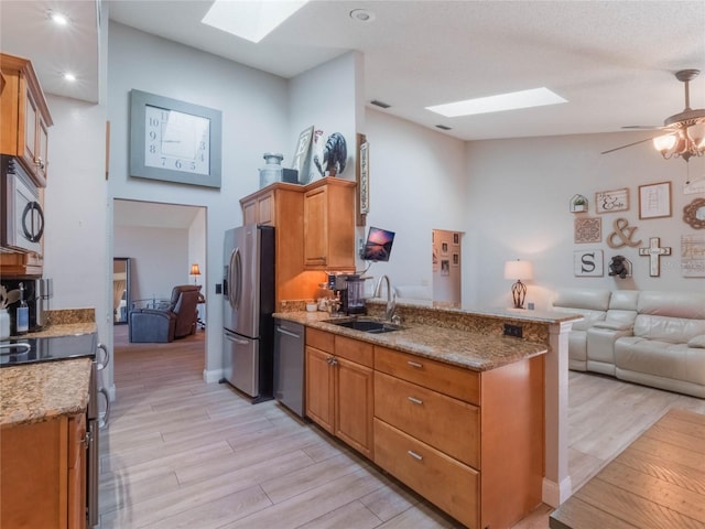 kitchen with appliances with stainless steel finishes, sink, and light wood-type flooring