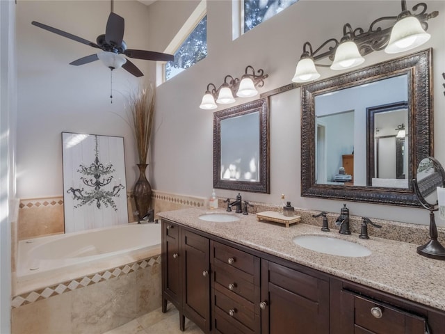 bathroom with vanity, tiled tub, and ceiling fan