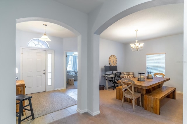 entryway featuring an inviting chandelier, light colored carpet, and plenty of natural light