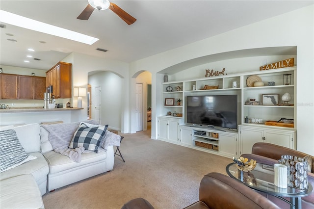 carpeted living room with built in shelves, vaulted ceiling, and ceiling fan