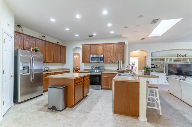 kitchen with stainless steel appliances, an island with sink, sink, and a breakfast bar