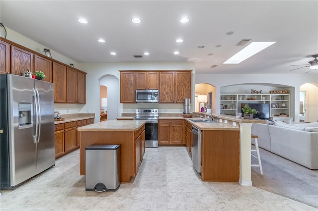 kitchen featuring sink, a breakfast bar area, kitchen peninsula, stainless steel appliances, and built in shelves