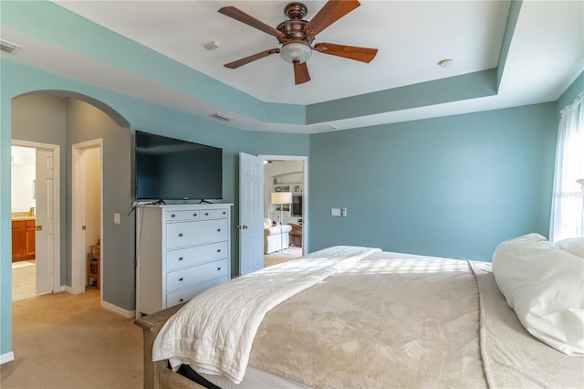 bedroom featuring a raised ceiling, light colored carpet, and ceiling fan